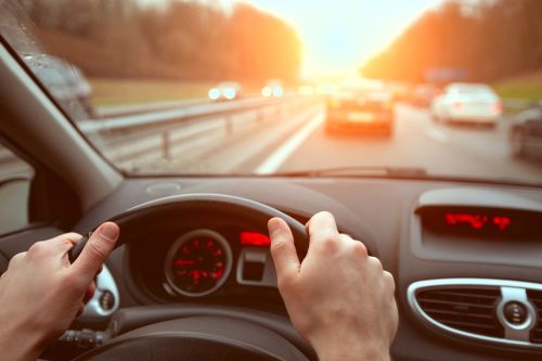 Driving on highway road, closeup hands of car driver on steering wheel.