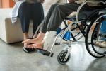Injured woman broken ankle wearing ankle support on wheelchair at the hospital after personal injury accident.